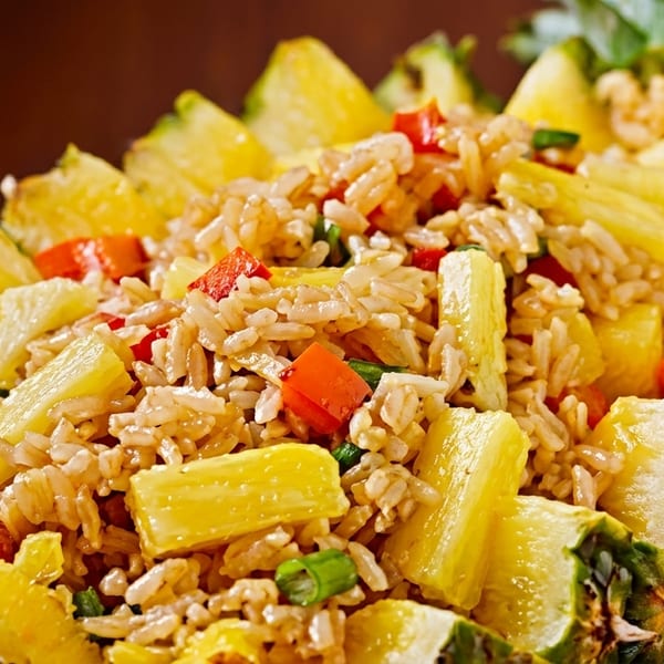 Pineapple fried rice with red peppers and green onions, served in a hollowed-out pineapple.